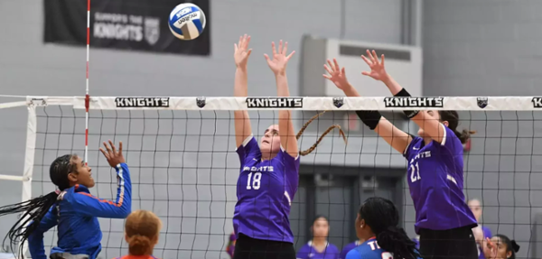 Knights volleyball players spike a ball during a game.